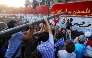 Egyptian protesters destroying a wall surrounding the Israeli Embassy in Cairo